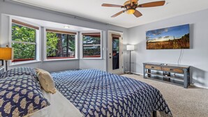 Ein Schlafzimmer mit Bett, Deckenventilator, Kommode und einem Bild an der Wand.