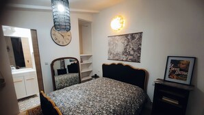 A bedroom with a bed, a dresser, a mirror, a clock, and a wall-mounted light fixture. - Very cocoon garden hut - access to our magnificent Gîte. Near Provins (Savins)
