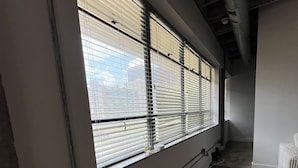 Una habitación con amplios ventanales, suelo de madera oscura y pared blanca.