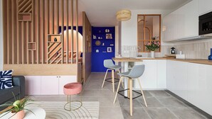 A modern kitchen with a wooden partition, a dining area with two chairs, and a kitchen island. - Cosy 33m2 studio with view of Monts d'Or & Lyon (Dardilly)