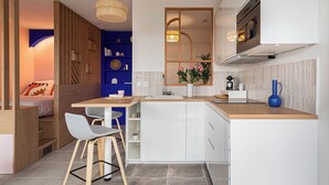 A modern kitchen with white cabinets, a wooden countertop, and a dining area with a table and chairs. - Cosy 33m2 studio with view of Monts d'Or & Lyon (Dardilly)