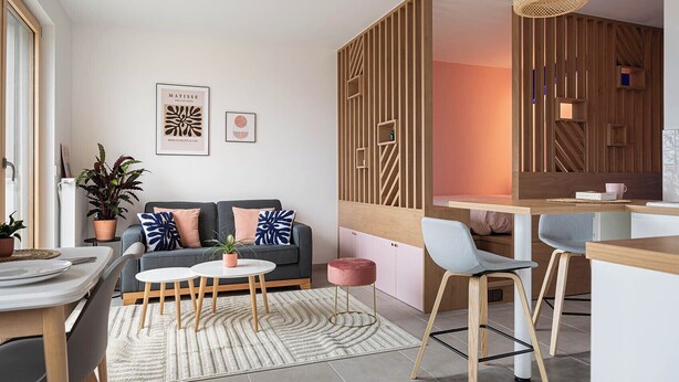 A modern living room with a sofa, coffee table, and chairs. There is a dining area with a table and chairs. The room has wooden paneling and a hanging light fixture. - Cosy 33m2 studio with view of Monts d'Or & Lyon (Dardilly)