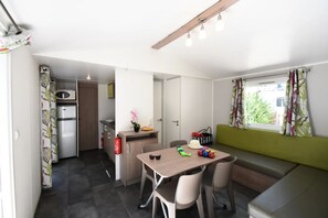 Eine kompakte Küche mit Mikrowelle, Kühlschrank und einer kleinen Essecke mit Tisch und Stühlen.