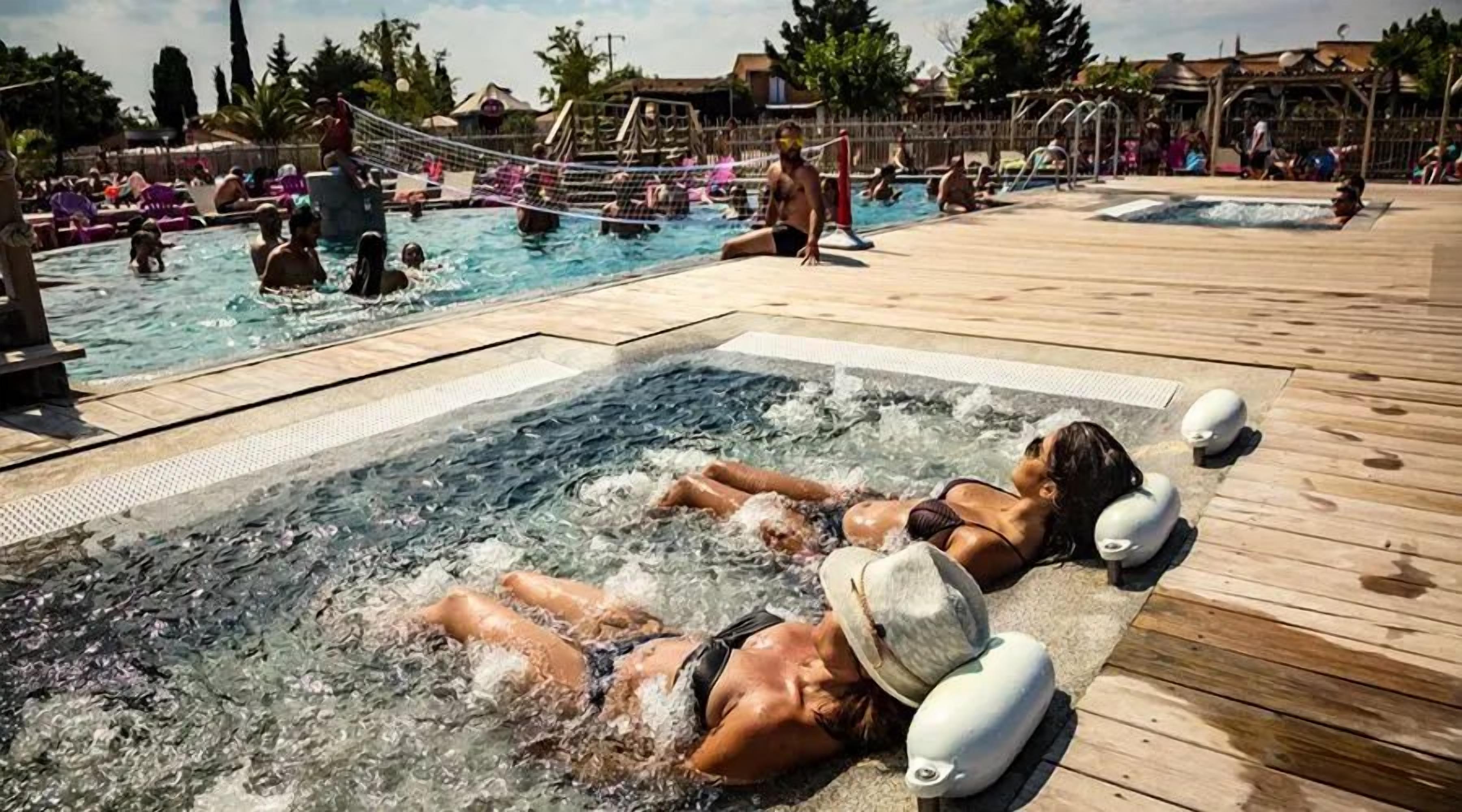 Un espace piscine comprenant plusieurs bassins et un jacuzzi.