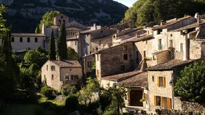 Un village historique aux bâtiments en pierre, avec une église et un paysage montagneux en toile de fond.