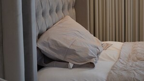 A bed with a tufted headboard and a neutral-colored pillow. - cozy 2-bedroom apartment with sea view in Al Khobar (Al Khobar)