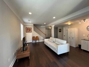 A spacious living area with a wooden dining table, a sofa, and a staircase leading to another room. - Luxury 3 BR 1.5 Baths Lower Level Unit: Nonsmoking (Arlington)
