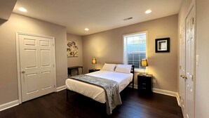 A bedroom with a bed, bedside tables, a window, and a door.