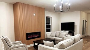Una sala de estar con chimenea, un sofá, una mesa de centro y un televisor.
