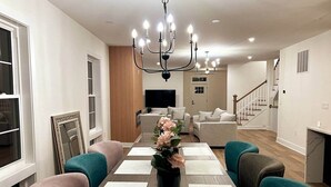 Un comedor moderno con una mesa de madera, sillas color turquesa y una araña.