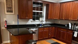 Een keuken met houten kastjes, een zwart aanrecht en een roestvrijstalen spoelbak.