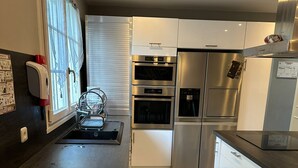 A modern kitchen with stainless steel appliances, a dishwasher, and a trash bin. - Spacious and pleasant (Garges-lès-Gonesse)