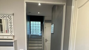 A hallway with a wooden floor, a staircase leading to a room with a window, and a door on the right. - Spacious and pleasant (Garges-lès-Gonesse)