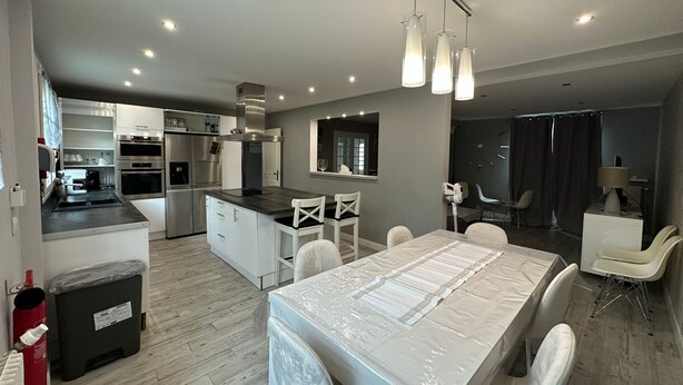 A modern kitchen with built-in appliances, a dining area with a table and chairs, and a living space with a sofa and a TV. - Spacious and pleasant (Garges-lès-Gonesse)