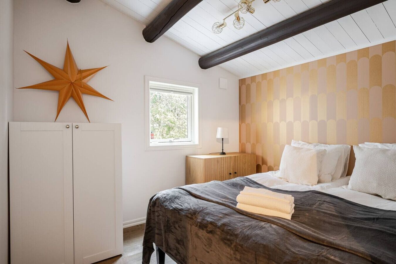 Une chambre à coucher avec un lit, une décoration en forme d’étoile, une fenêtre et une tête de lit en bois.