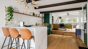 Une cuisine moderne dotée d’un plan de travail en marbre, de tabourets de bar et d’un luminaire original.