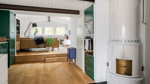 Un grand salon comprenant un canapé, une table basse et une plante en pot. Un escalier mène à une autre pièce.
