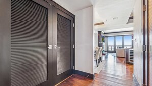 A hallway with a dark wooden door, a wooden floor, and a view into a dining area with chairs and a table. - Northstar Resort Mid-Mountain Ski in/Ski in/Ski out 3 bedroom condo (Truckee)