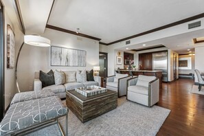 A modern living room with a sofa, armchairs, a coffee table, and a kitchen in the background. - Three-Bedroom · 3.5 Bath · Top-Floor · Sleeps 8 (Truckee)