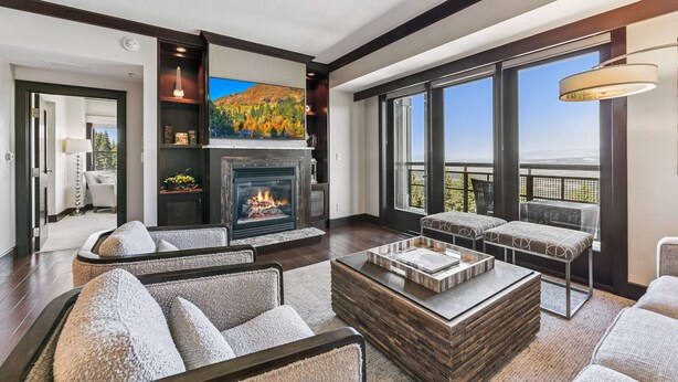 A spacious living room with a fireplace, comfortable seating, and large windows offering a view. - Northstar Resort Mid-Mountain Ski in/Ski in/Ski out 3 bedroom condo (Truckee)