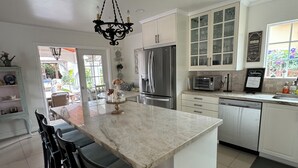 A modern kitchen with a central island, white cabinetry, stainless steel appliances, and a chandelier.