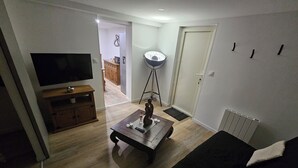 A living room with a flat-screen TV, a coffee table, a sofa, and a floor lamp. - Apparently (Naintré)