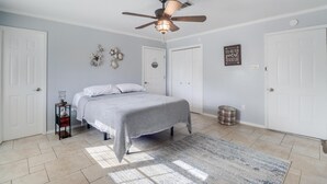 Une chambre à coucher avec un lit, un ventilateur de plafond, un tapis et un élément décoratif mural.