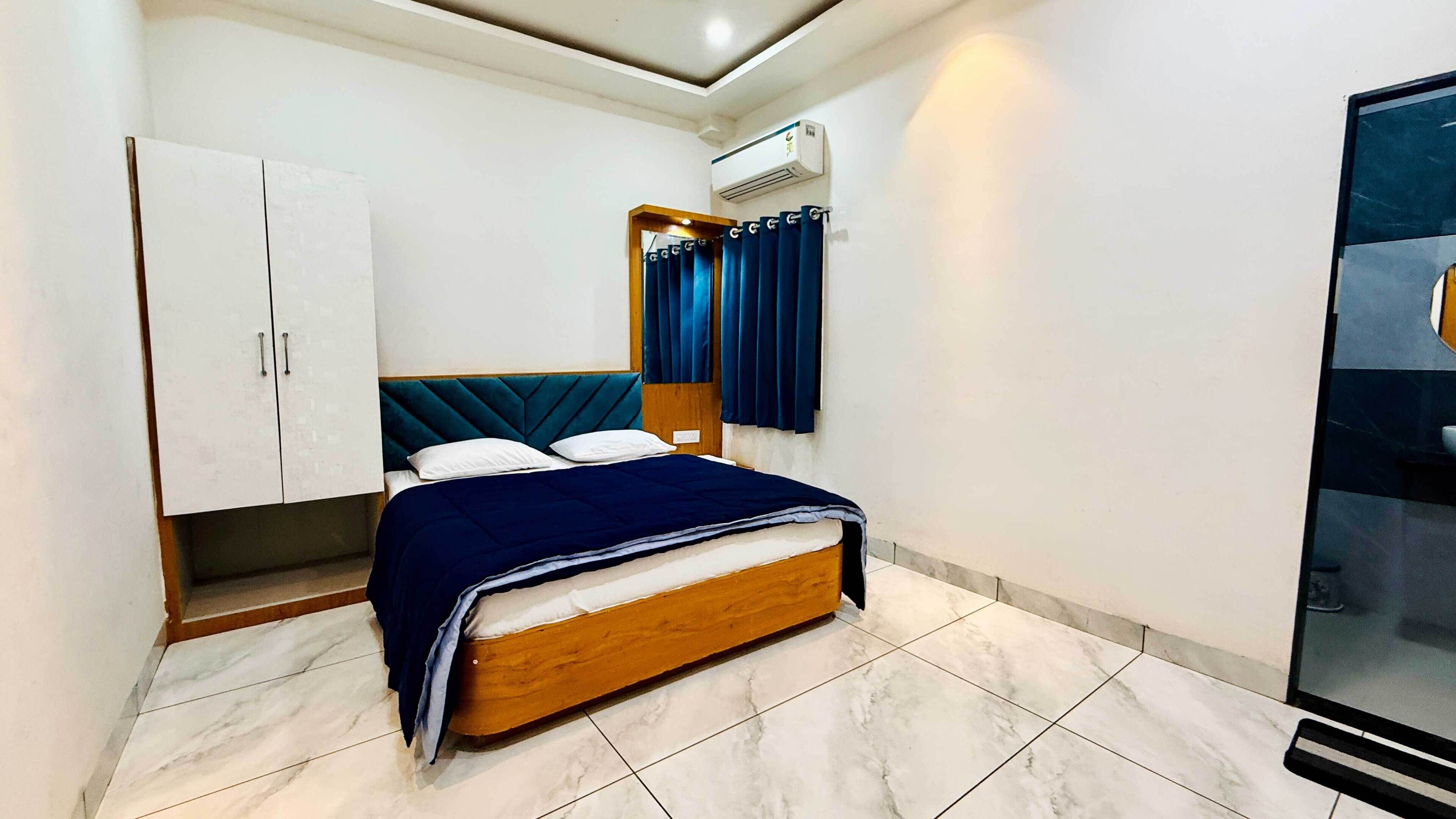A bedroom with a bed, wardrobe, and an air conditioning unit.