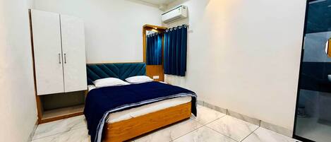 A bedroom with a bed, wardrobe, and an air conditioning unit.