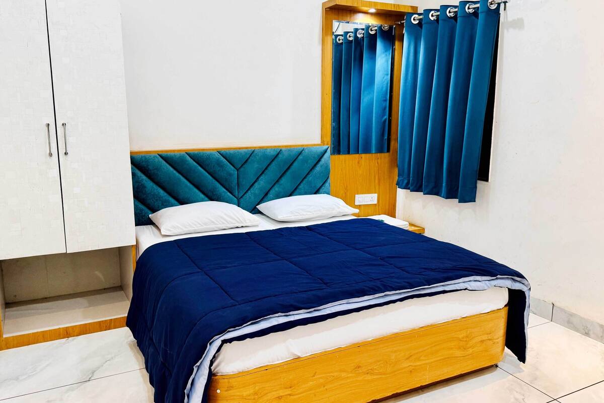 Un dormitorio con una cama, cortinas blancas y un cabecero de madera.