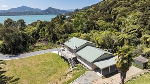 A single-story building with a green roof, surrounded by lush greenery and a clear view of a lake. - Kereru Retreat at Moetapu Bay (Moetapu Bay)
