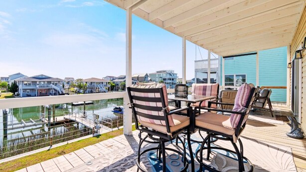 Une terrasse extérieure couverte offrant une vue sur un port de plaisance et des maisons.