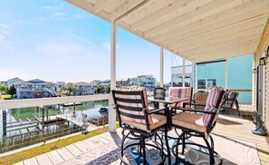 Une terrasse extérieure couverte offrant une vue sur un port de plaisance et des maisons.