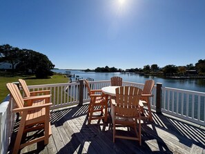 Um deck de madeira com uma mesa e cadeiras, com vista para a água.
