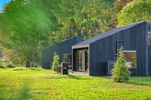 A modern two-story building with a dark exterior, large windows, and a small porch area.