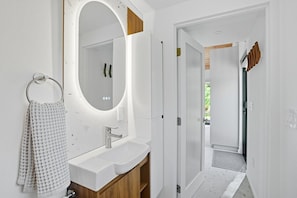 A modern bathroom with a large mirror, a sink, and a towel rack.