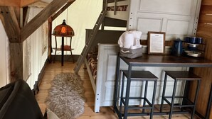 Een gezellige slaapkamer op zolder met een stapelbed, een klein tafeltje met krukjes, een lantaarn en een lijst met certificaat aan de muur.