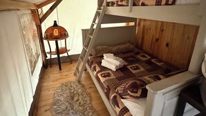 Een slaapkamer met een stapelbed, een tafeltje met een lamp en een zacht tapijt op de vloer.