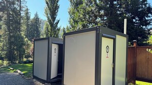 Mobiele toiletten met rookverbod, gelegen in een bebost gebied met een houten hek.
