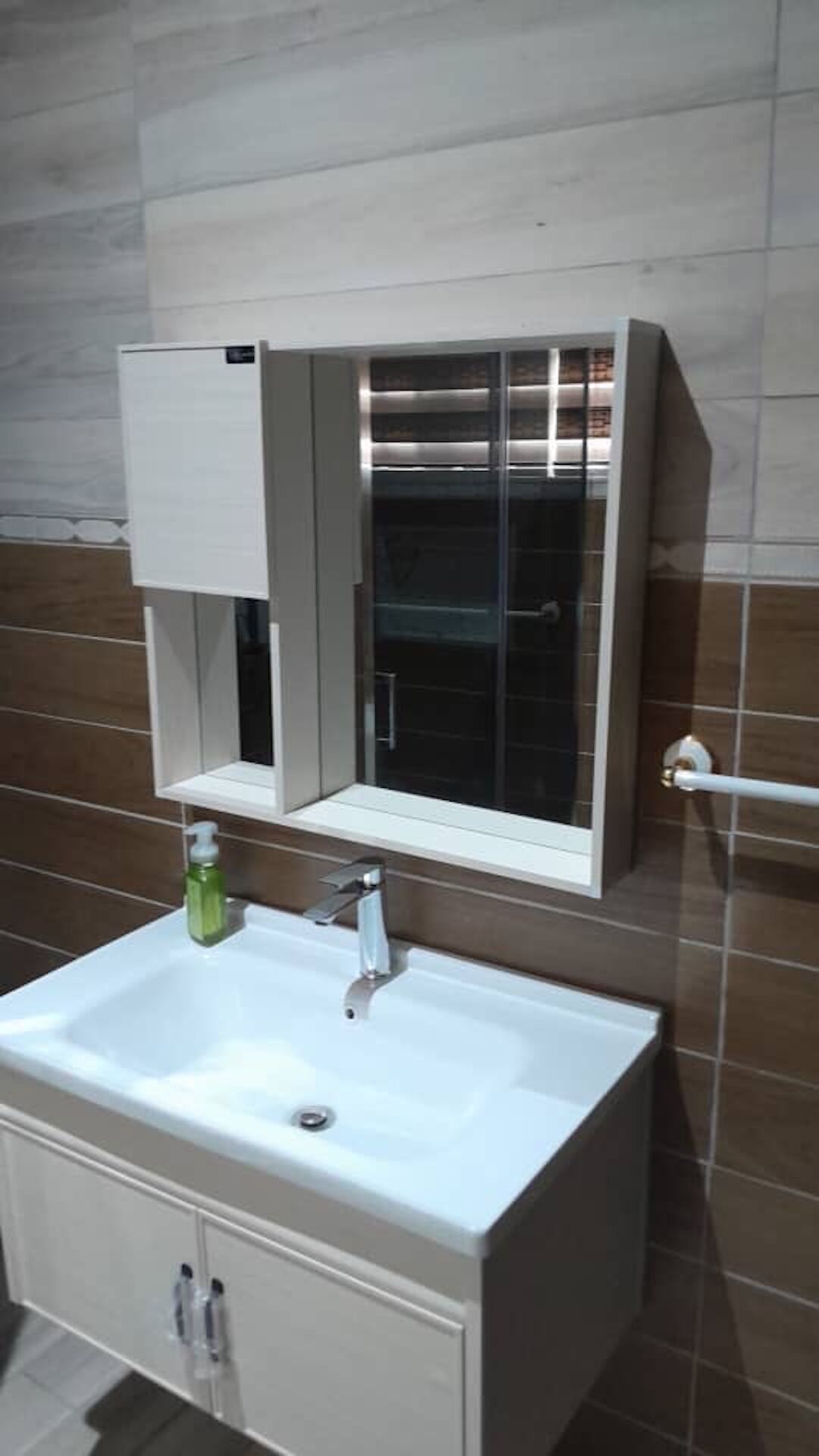 Une salle de bain avec un lavabo blanc, un miroir et un porte-serviettes.