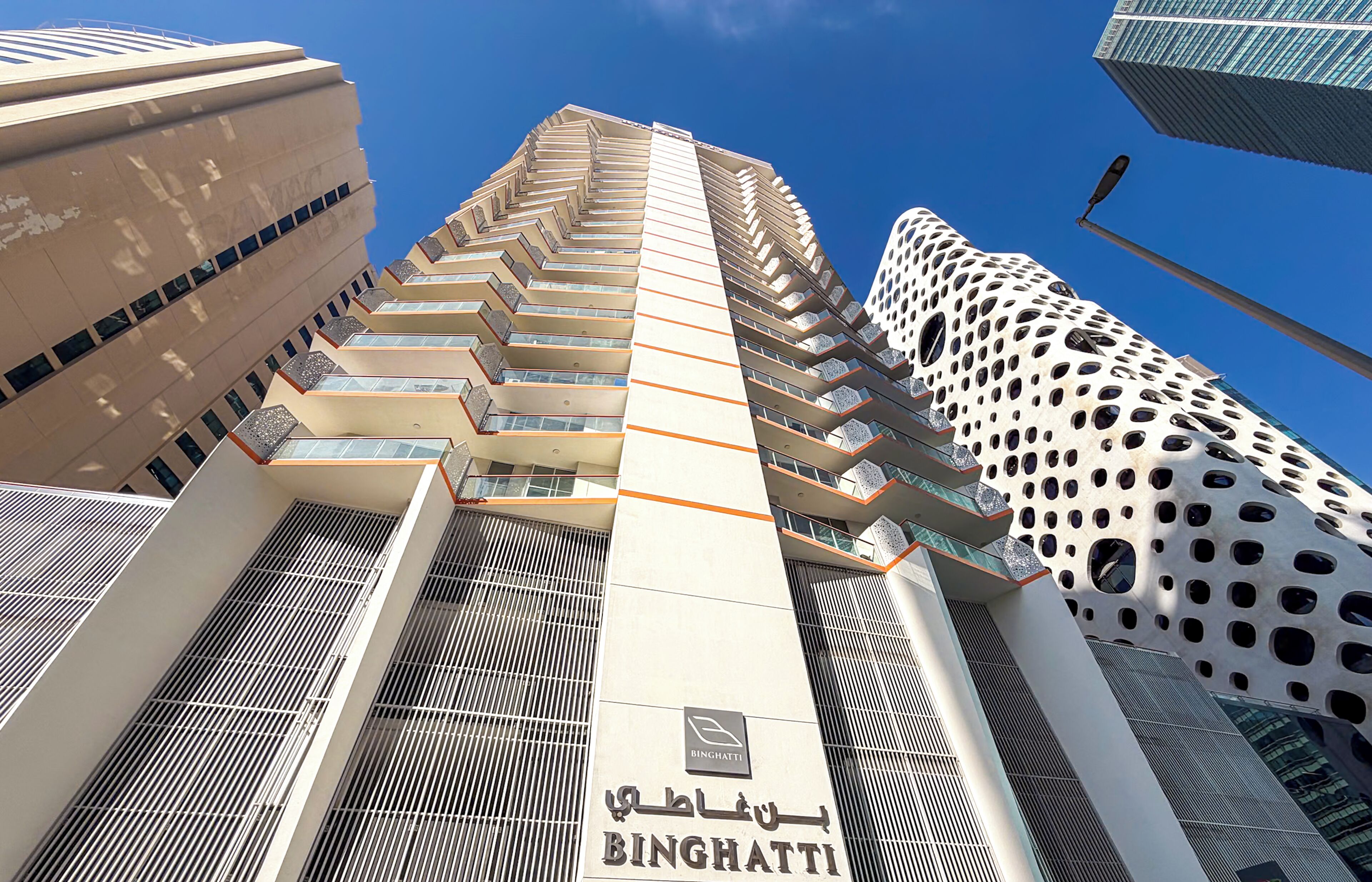 A high-rise building with a distinctive perforated facade and a clear blue sky.