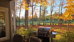 Un patio con una parrilla, sillas y vistas a un campo de golf.