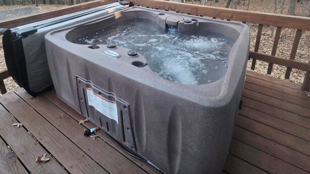 Ein Whirlpool auf einer Holzterrasse mit Blick auf den Wald.