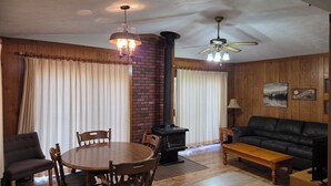 Ein gemütliches Wohnzimmer mit Kamin, einem Esstisch mit Stühlen, einer Couch und einem Deckenventilator.