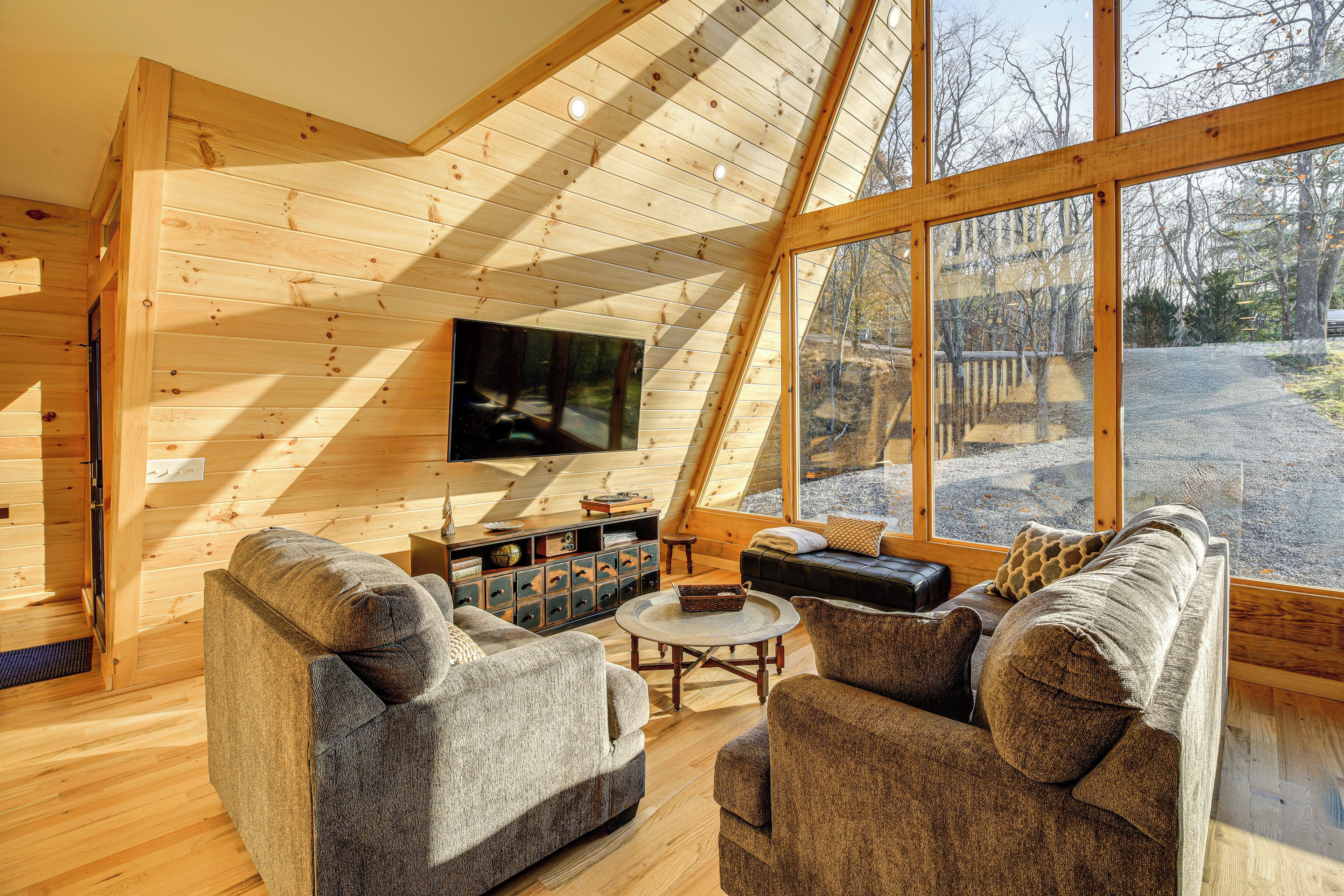 A cozy, wooden interior with a large window, a flat-screen TV, and comfortable seating.