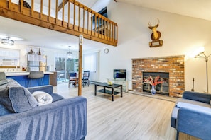 A living room with a fireplace, a dining area, and a kitchen. - Ski, Swim & Hike! Family Home in Tobyhanna (Tobyhanna)