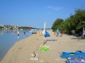A beach with a sandy shore, a few umbrellas, and a calm body of water. - Comfort Two Bedroom Apartment with Terrace (Rogoznica)