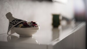 Un bol en céramique blanche orné d’un motif décoratif sur le couvercle, posé sur une surface réfléchissante.