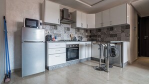 Une cuisine moderne avec des meubles blancs, un four encastré, un four à micro-ondes et un lave-linge.