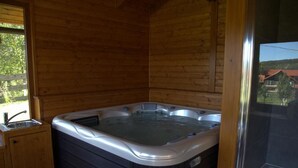 A wooden cabin with a hot tub, a window, and a door leading outside. - Brezova Poljana Lodge with Sauna and Hot-Tub - Five Bedroom Holiday Home (Vrbovsko)